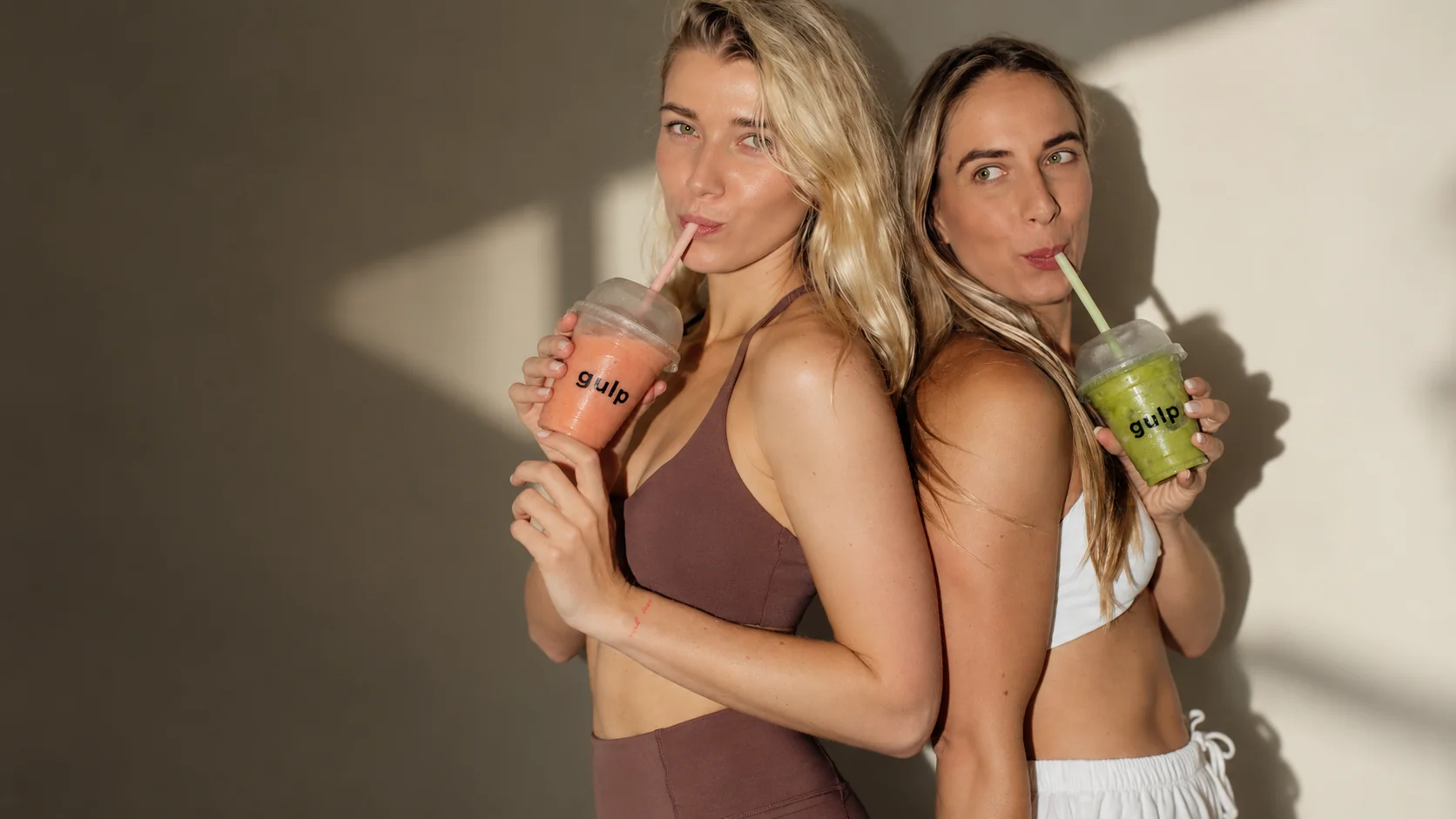 Two women drinking Gulp smoothies through straws
